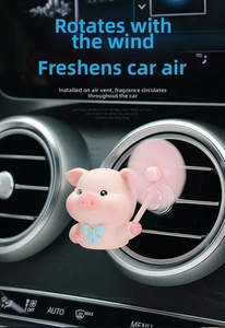 Pink cartoon pig car air freshener with a rotating fan mounted on a black vent