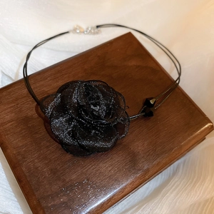 Detail of black double-layered lace choker necklace with crystal beads on wooden box