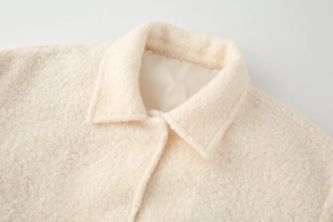 Detailed close-up of thick beige sherpa wool fabric texture on lapel collar jacket