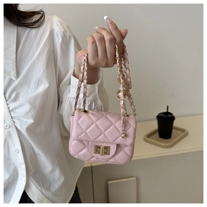 Close-up of pink quilted mini bag with gold chain strap held by a model in casual attire