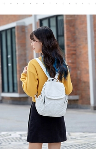 Zaino bianco in morbida pelle con cerniere a nappa e tasche multiple sulla modella