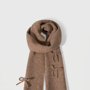 Brown wool blend knitted scarf featuring elegant bow accents for winter warmth
