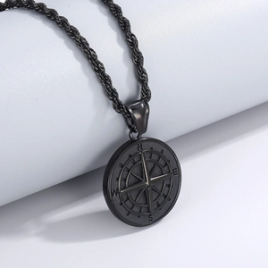 Gros plan d'un pendentif boussole noir avec chaîne torsadée en acier titane poli