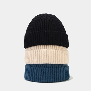 Vertical stack of high-quality knit beanies in black, beige, and blue ribbed texture