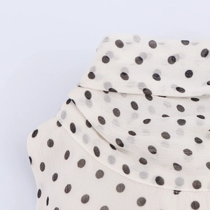 Detailed view of the elegant high neck design and soft pleated texture on polka dot dress