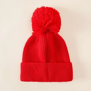 Detailed view of red knitted Christmas hat with large soft pom pom and warm texture