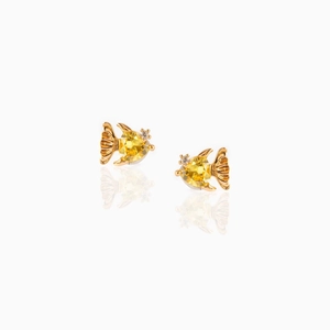Macro detail of creative fish stud earrings with yellow faceted gemstones and gold plating