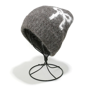 Detailed view of dark grey knitted hat with fuzzy mohair texture and white bow pattern