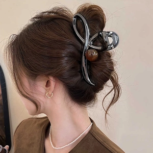 Minimalist dark gunmetal crossover hair claw clip with amber bead on model's hair