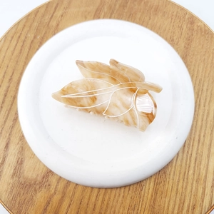 Detail of leaf-shaped hair claw with marble texture and white vein lines on round tray