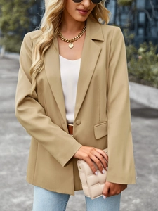 Detail of khaki short sleeve blazer featuring a gold chain and woven clutch bag