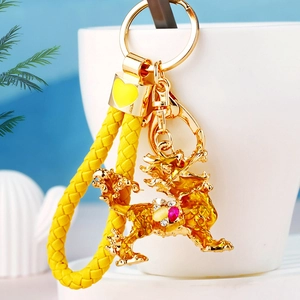 Detail of golden dragon keychain with colorful rhinestones on a yellow woven cord