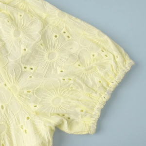 Detail of yellow cotton dress sleeve featuring delicate eyelet floral embroidery and elastic cuff