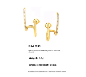 Detailed macro of golden J-shaped stainless steel earrings with sparkling zircons