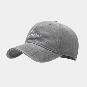 Detailed view of white 'Groom' cursive embroidery on a vintage washed grey cotton baseball cap