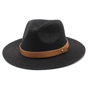 Détail d'un chapeau fedora en paille noire avec ruban en cuir marron et rivet doré chic