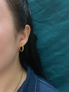 Close-up of gold hoop earrings with zircon pavé setting worn by model on green fabric