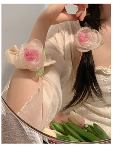Detail of pink organza rose hair tie and wrist flower with layered fabric petals