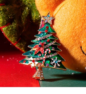 Close-up of a festive Christmas tree brooch with green enamel and colorful rhinestones