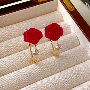 Detail of red flocked flower earrings with gold rings and sparkling geometric crystals