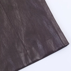 Primer plano de cuero sintético marrón oscuro con textura de grano y detalle de costura