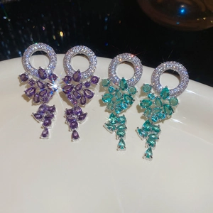 Détail macro de boucles d'oreilles argentées avec cristaux poire violets et vert lagon