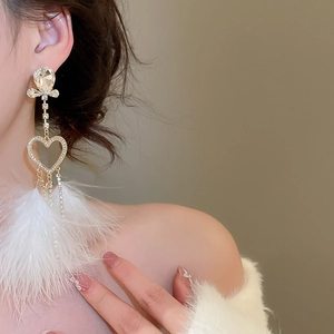Detail of long tassel feather earrings with heart elements on a model for a chic style