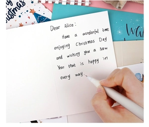 Gros plan d'une carte de Noël pliable avec stylo à bille assorti et message manuscrit