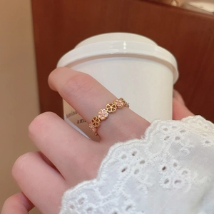 Detail of gold floral ring with pink enamel clovers worn in a cozy lifestyle setting