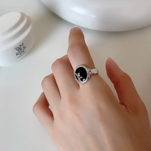 Detail of silver S925 ring with black agate and embossed tulip floral design on finger