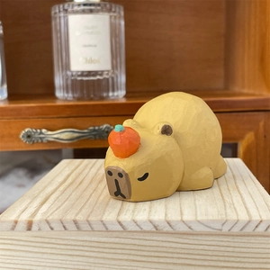 Close-up of a carved wooden capybara figurine with a small orange on its head