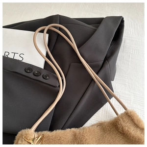 Close-up of soft brown plush faux fur texture and beige leather shoulder strap detail