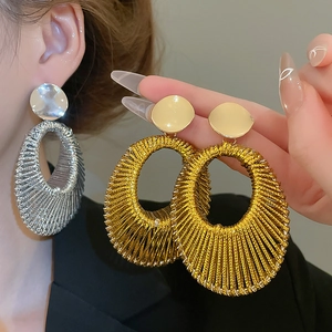 Détail de grandes créoles tressées dorées et argentées avec texture en maille métallique