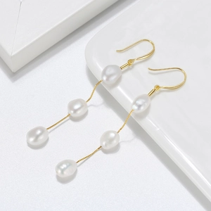 Detailed macro view of three white baroque pearls on a gold chain drop earring