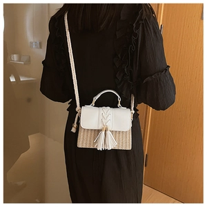 Model view showing the crossbody straw bag with white fringe and braided strap details