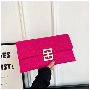 Gros plan sur la pochette fuchsia à motif crocodile et fermoir doré géométrique