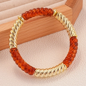 Bracelet géométrique en métal doré et acrylique ambré présenté dans son écrin à bijoux