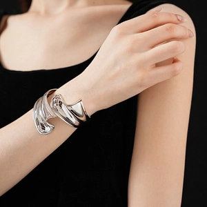 Irregular liquid metal open cuff bracelet in polished silver on a model's wrist