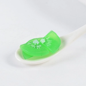 Macro shot of artificial kiwi slices with green texture and black seeds in a spoon