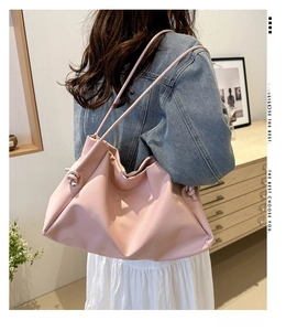Detail of pink faux leather tote bag showing embossed lettering and pleated top closure