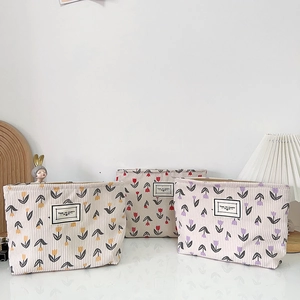 Three beige corduroy makeup bags with tulip floral patterns on a white table
