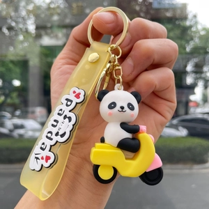 Detail of cute panda toy on a yellow scooter with a matching silicone keychain strap