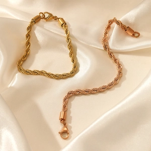 Elegant gold and rose gold twisted rope bracelets with lobster clasp on silk background