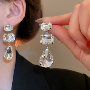 Detailed close-up of long silver fringe earrings with sparkling drop-shaped crystal stones