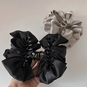 Elegant French style silk bow claw clips in black and beige displayed in hand
