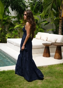 Détail d'une robe maxi à volants dos nu bleu marine avec de fines bretelles de plage