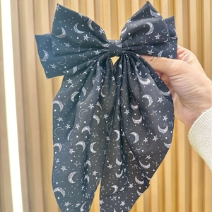 Large black bow hair clip with white star and moon prints and elegant long ribbons