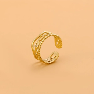 Detail of gold double-layered adjustable ring with chain and bead textures on beige background