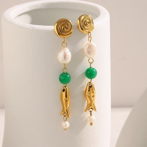 Detail of 18K gold plated fish drop earrings with pearls and green stone on ceramic