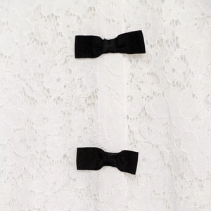 Detailed macro view of white lace fabric texture featuring two black decorative bows
